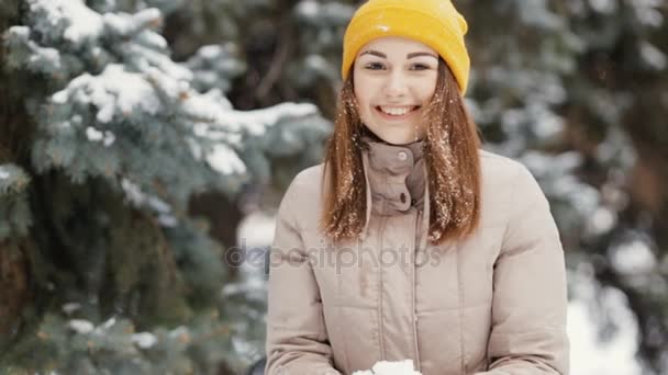 Счастливая молодая женщина бросает снег в воздух, замедленная съемка. Она наслаждается зимой . — стоковое видео