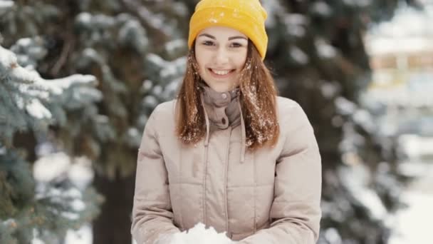 Счастливая молодая женщина бросает снег в воздух, замедленная съемка. Она наслаждается зимой . — стоковое видео