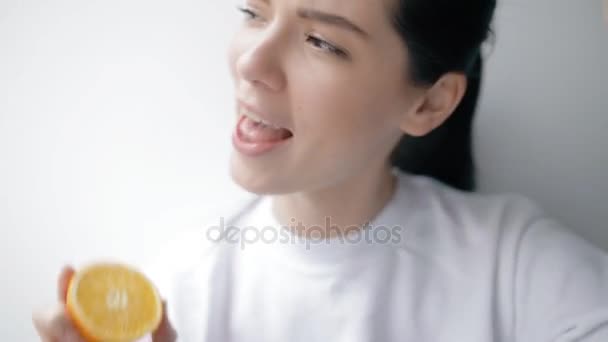 Забавная женщина играет обезьяну с апельсиновыми фруктами — стоковое видео