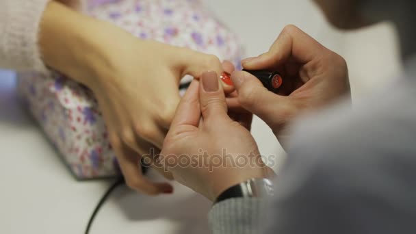 Cosmético cubre con precisión las uñas del cliente con esmalte de uñas rojo — Vídeo de stock