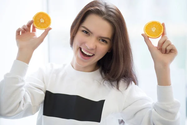 Kvinna med orange frukt leende på vit bakgrund — Stockfoto