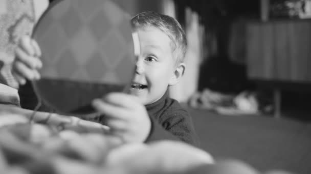 Chlapec hrající se zrcadlem v domácím místnosti. Černobílý tisk. — Stock video
