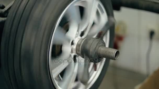 Serviço de pneus. Mecânico equilibrar uma roda de carro na máquina automatizada . — Vídeo de Stock