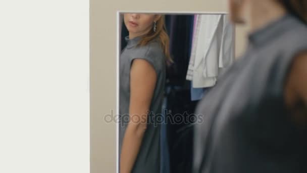 Женщина примеряет одежду в магазине, стоя перед зеркалом — стоковое видео