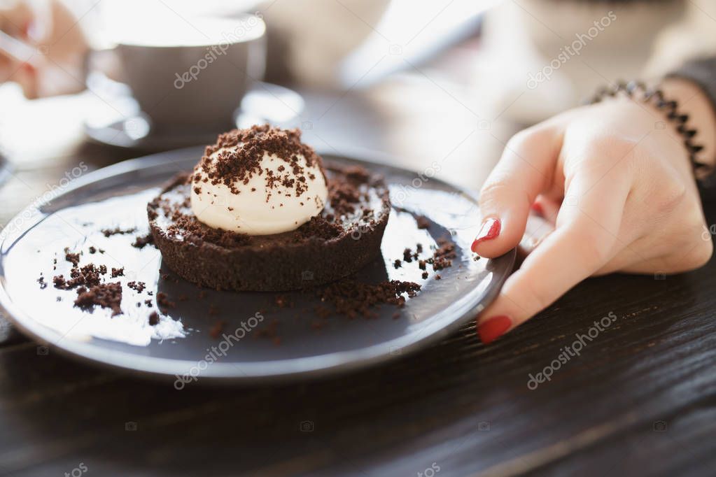 Female hand taking a sweet cake on saucer