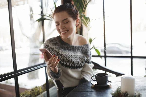 Nainen kirjoittaa tekstiä älypuhelin kahvilassa, kun kahvi on jäähtyy — kuvapankkivalokuva