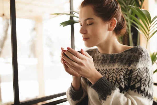 Mujer en jersey disfrutar del aroma de cappuccino en un café — Foto de Stock