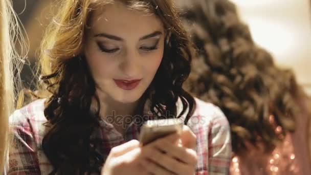 Женщина смотрит на свой смартфон внутри — стоковое видео