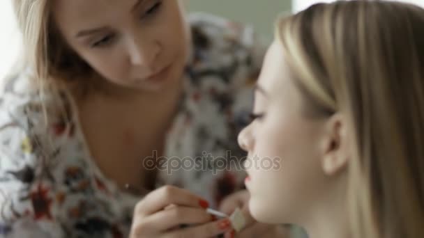 Master doet make-up voor model met behulp van lippenstift — Stockvideo