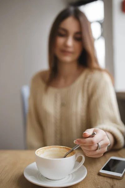 Mujer revuelva la cuchara de azúcar en la taza de capuchino en la cafetería — Foto de Stock