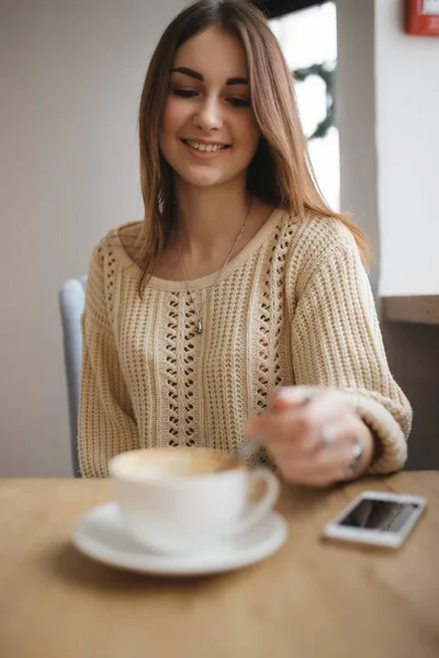 Nainen sekoita sokeri lusikka kuppi cappuccino kahvilassa — kuvapankkivalokuva