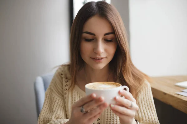Preciosa mujer soplando en una taza de café en un café — Foto de Stock