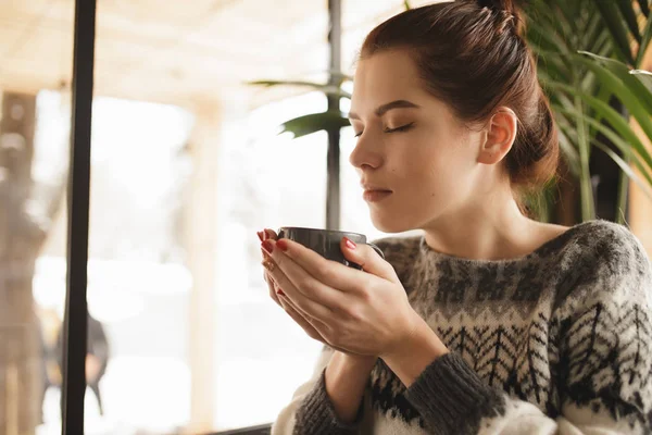 Mujer en jersey disfrutar del aroma de cappuccino en un café — Foto de Stock