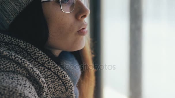 Портрет крупным планом женщины в очках, смотрящей в окно — стоковое видео