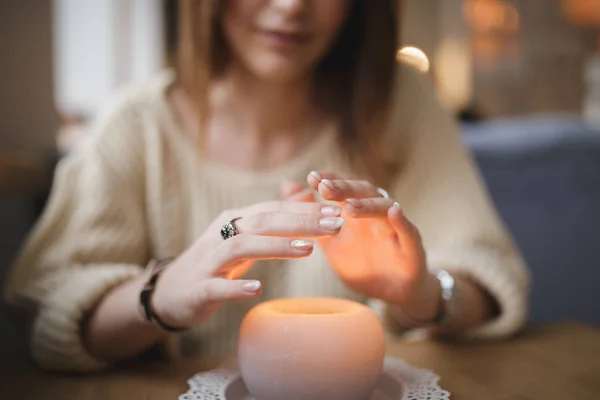 Mulher que aquece mãos acima da vela - tiro cortado — Fotografia de Stock