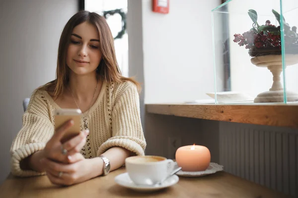 女人对智能手机的一家咖啡馆，而咖啡是打字文本冷却 — 图库照片