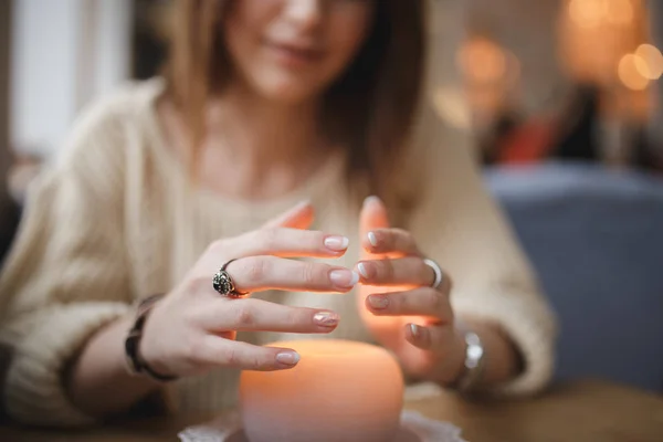 Kvinna som värmer händerna ovanför candle - beskurna sköt — Stockfoto