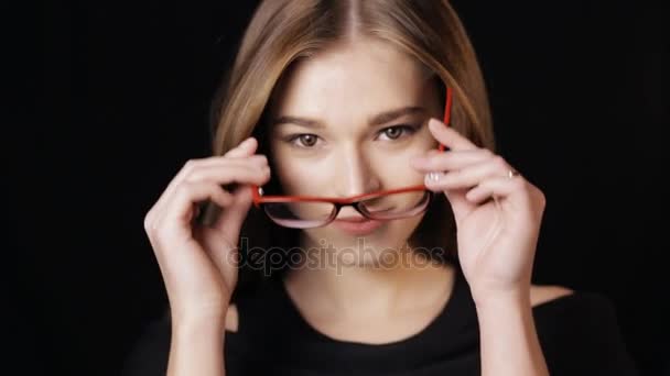 Primer plano de la atractiva mujer con anteojos en el fondo negro — Vídeos de Stock