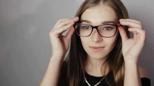 Closeup ελκυστική γυναίκα που φοράει γυαλιά στο γκρίζο φόντο — Αρχείο Βίντεο