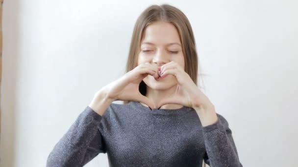 Adolescente avec bretelles faire l'amour geste de coeur avec les mains — Video