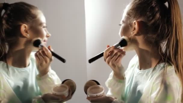 Adolescente chica en windcheater hacer maquillaje antes de espejo — Vídeo de stock