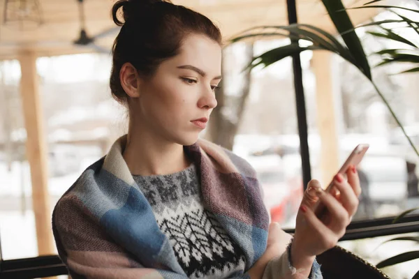 Женщина печально смотрит на смартфон в кафе — стоковое фото