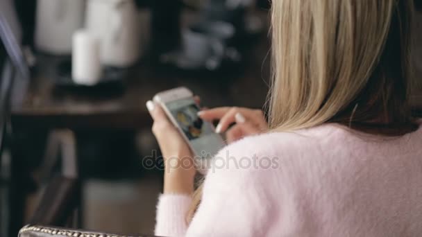 Mujer sentada en un café y mirando el teléfono inteligente - vista trasera — Vídeos de Stock