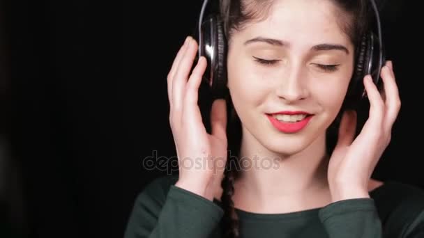 Vrouw in koptelefoon luisteren muziek op zwarte achtergrond — Stockvideo