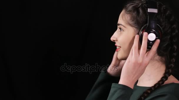 Nő a fülhallgató, hallgatni a zenét a fekete háttér - hossz-szelvény nézet — Stock videók