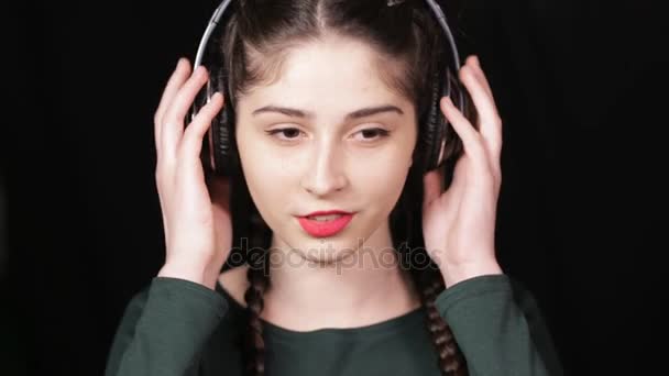 女人在耳机听音乐在黑色背景上 — 图库视频影像
