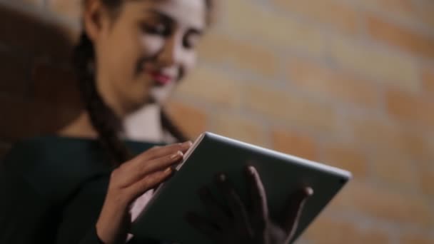 Vrouw met behulp van tablet Pc bij bakstenen muur achtergrond in een donkere kamer — Stockvideo