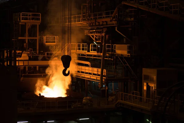 Metallurgical plant, liquid metal in container. Big crane hook.