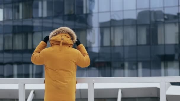 Неузнаваемый человек в желтой зимней куртке в центре города. Пар изо рта . — стоковое видео