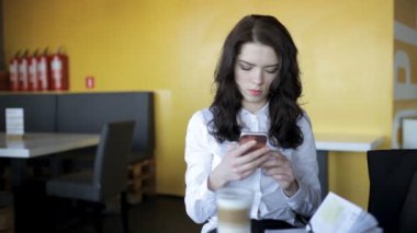 Modern nesil. Latte cools ise kafede smartphone kullanan kadın.