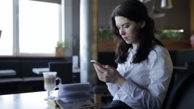 Modern nesil. Latte cools ise kafede smartphone kullanan kadın.