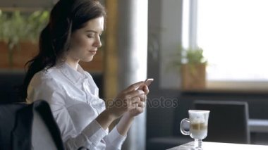Smartphone kullanarak ve bir kafede kahve içme güzel kadın