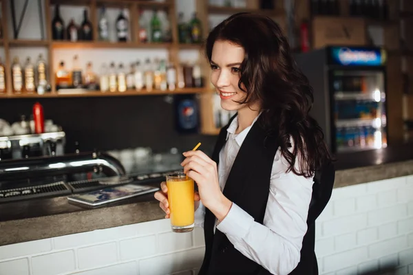 Beautiful woman holding glass of fresh orange juice at restaurant bar. Health trend. — Stock Photo, Image