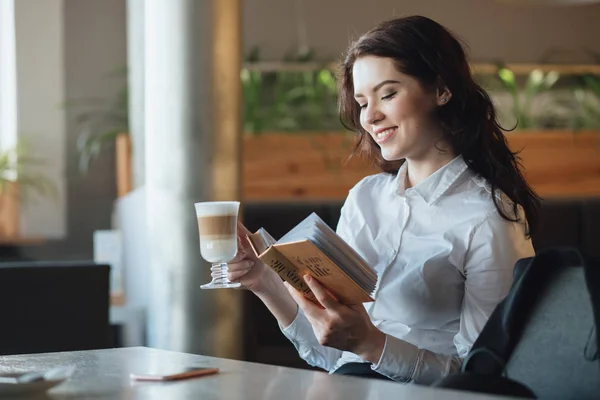 Jeune femme se détendant au café, buvant du latte, lisant un journal intime — Photo