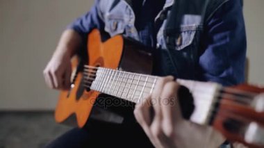 Gri duvar arka plan oturup gitar çalmaya gitarist