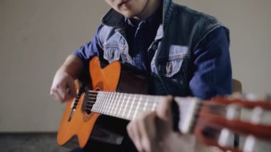 Akustik gitar gri duvar arka plan oturan oynayan erkek gitarist