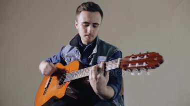Akustik gitar gri duvar arka plan oturan oynarken gitarist