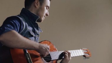 Akustik gitar gri duvar arka plan oturan oynayan adam gitarist