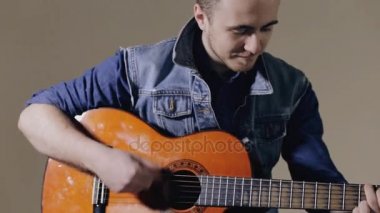 Akustik gitar gri duvar arka plan oturan oynarken gitarist