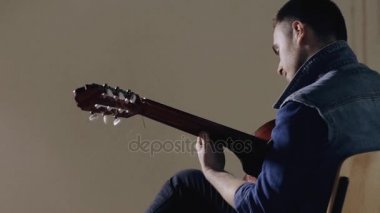 Akustik gitar gri duvar arka plan oturan oynarken gitarist