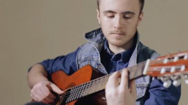 Akustik gitar gri duvar arka plan oturan oynarken gitarist