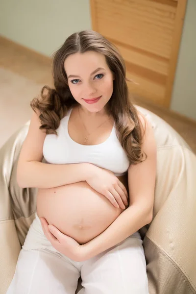 Kobieta w ciąży, siedząc na pufę w domu — Zdjęcie stockowe