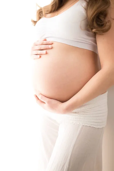 Обрезанный снимок беременной женщины с большим животом на белом фоне — стоковое фото