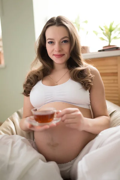 임신한 여자 가정에서 pouf에 앉아서 마시는 차 — 스톡 사진