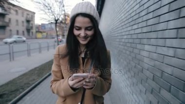 Genç kadın şehirde yürüyüş sırasında smartphone cep telefonu ile mesaj yazarken