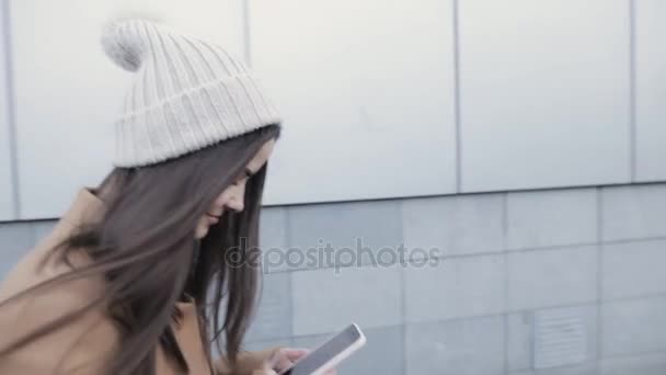 Jovem mulher escrevendo sms no smartphone enquanto caminha na cidade — Vídeo de Stock